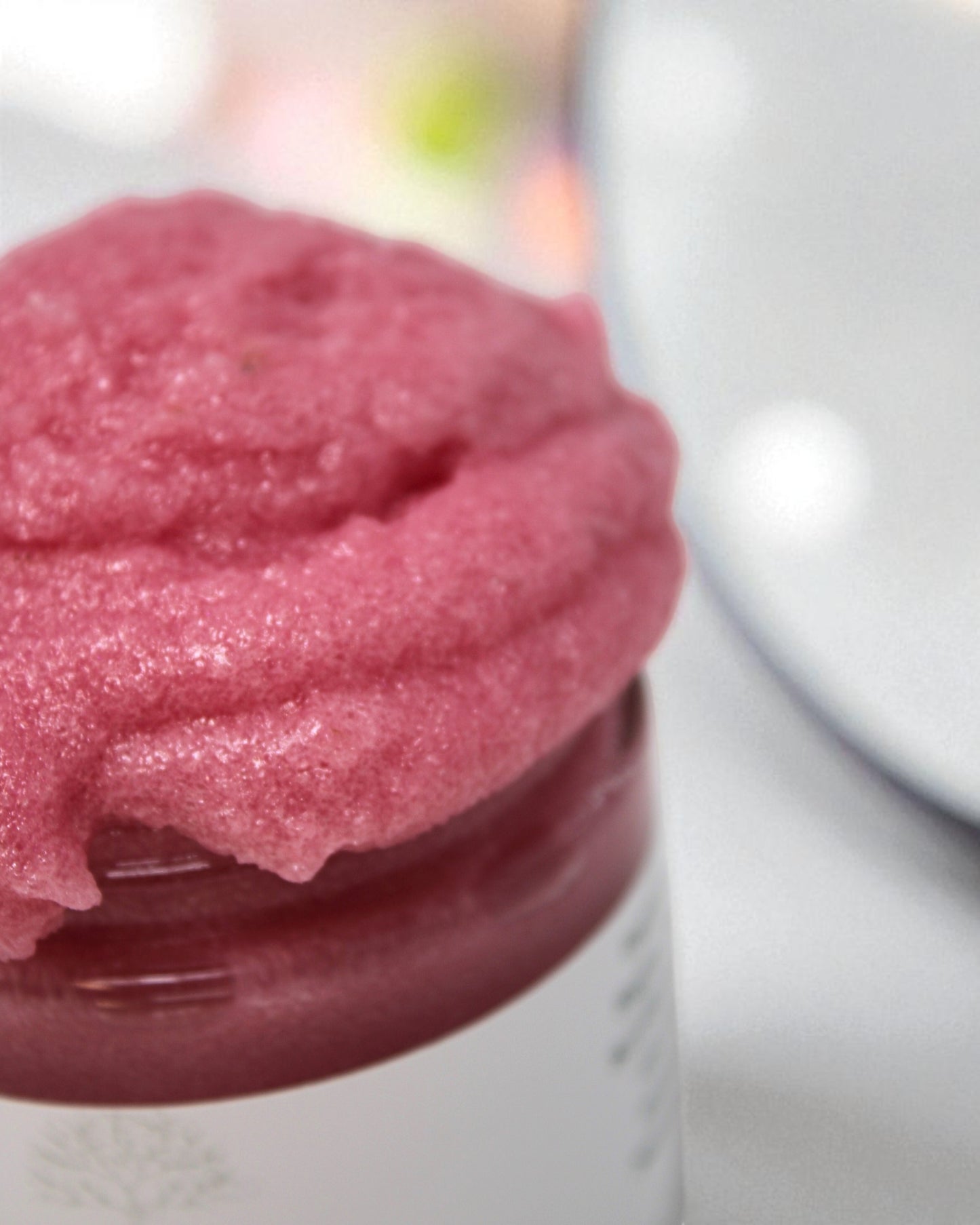 Close-up of a pink textured product in a jar with a blurred background