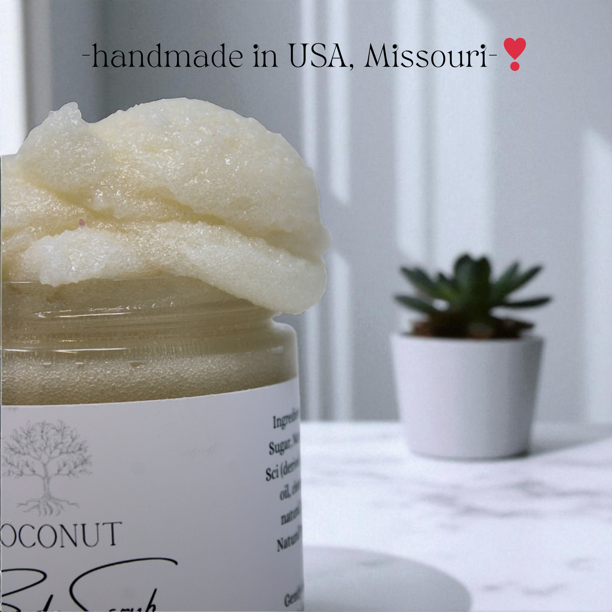 Jar of coconut body scrub with a plant in the background, labeled 'handmade in USA, Missouri'.