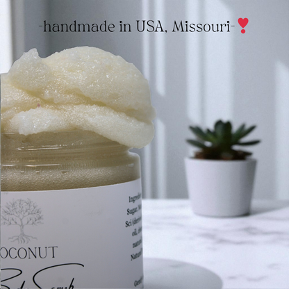Jar of coconut body scrub with a plant in the background, labeled 'handmade in USA, Missouri'.